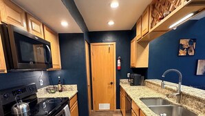 A kitchen with wooden cabinets, a microwave, stove, granite countertops, and a sink. - The best views in Frisco. Highest, corner unit, 600 feet to water's edge. (Frisco)