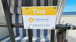 En strandstol med en skylt där det står ”Tine” samt ett telefonnummer och en webbadress.