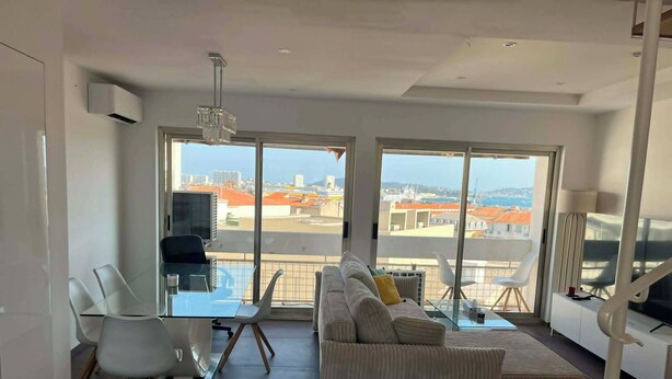 Ein modernes Wohnzimmer mit einer großen Couch, einem Esstisch mit Stühlen und einem Fernseher.