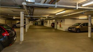 Eine mehrstöckige Parkgarage mit Betonböden und weißen Säulen, mit mehreren parkenden Autos und sichtbarer Beschilderung.