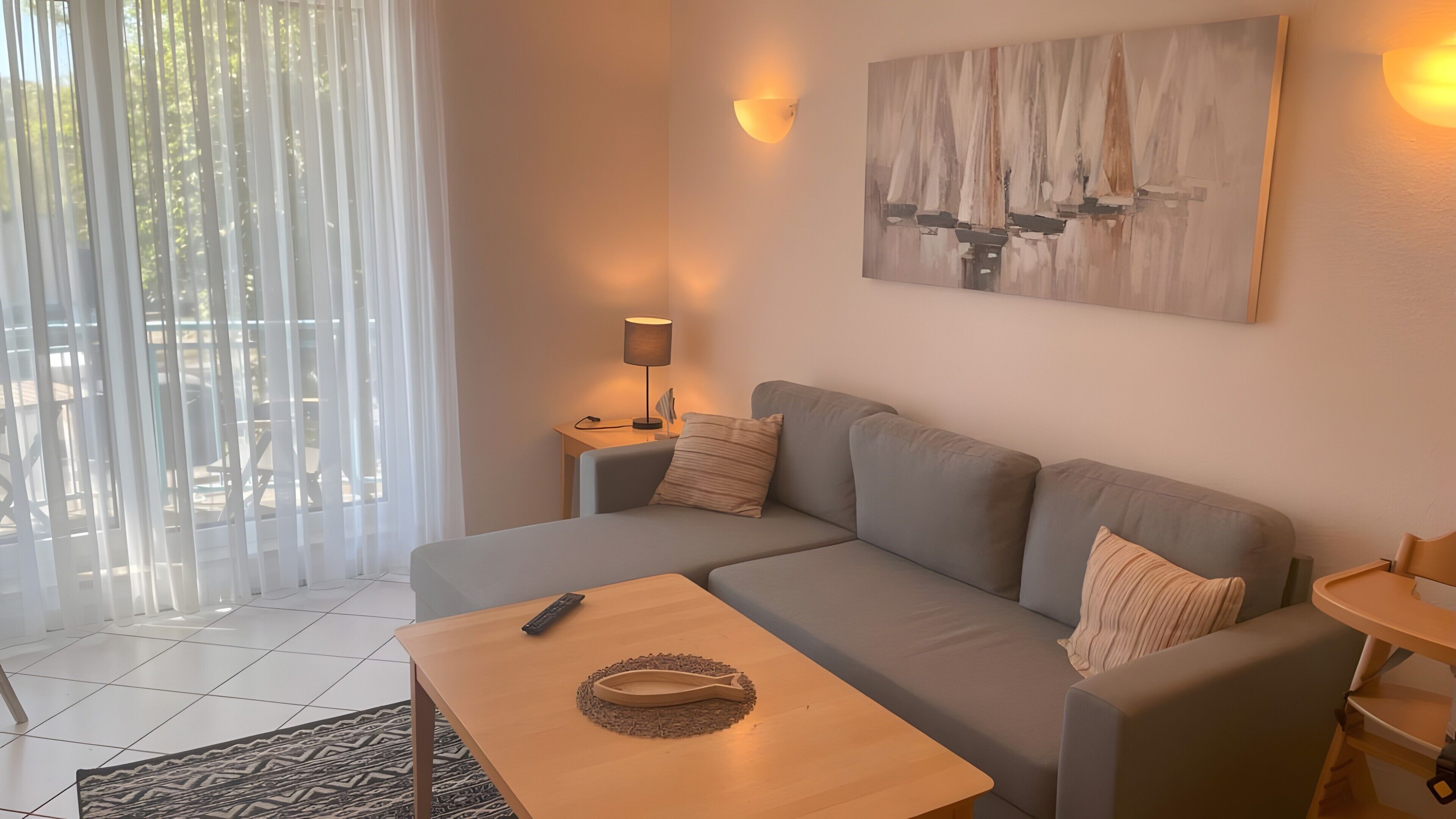 Uma sala de estar moderna com sofá, mesa de centro, abajur e um quadro na parede.