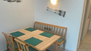 A dining area with a wooden table, four green placemats, wooden chairs, and a wall-mounted light fixture. - Apartment “Giovanni” with Balcony and Wi-Fi (Zempin)