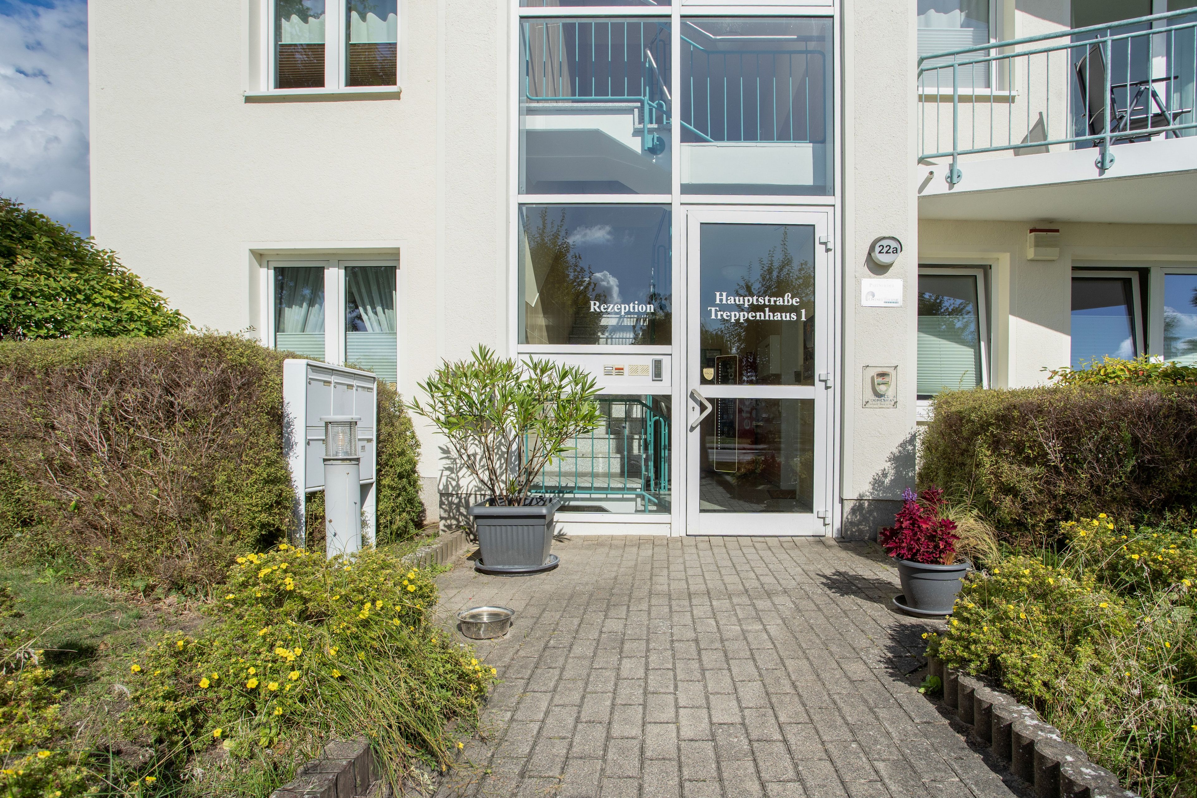 Une entrée d’immeuble comprenant un espace d’accueil, un escalier et une signalétique indiquant « Hauptstraße, escalier n° 1 ».