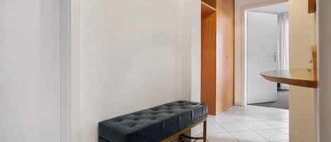 A hallway with a bench, a wooden door, and a light fixture.