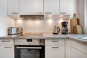 A modern kitchen with a built-in oven, a coffee maker, and a toaster. - Apartment 'Astra' with Balcony and Wi-Fi (Zempin)