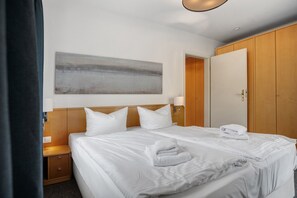 Une chambre d’hôtel avec deux lits, un grand tableau au mur, une armoire et une porte de salle de bain.
