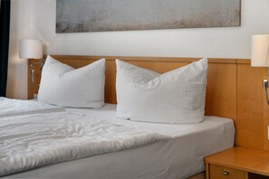 A hotel room with two beds, white bedding, a wooden headboard, a nightstand, and a wall-mounted lamp. - Apartment 'Astra' with Balcony and Wi-Fi (Zempin)