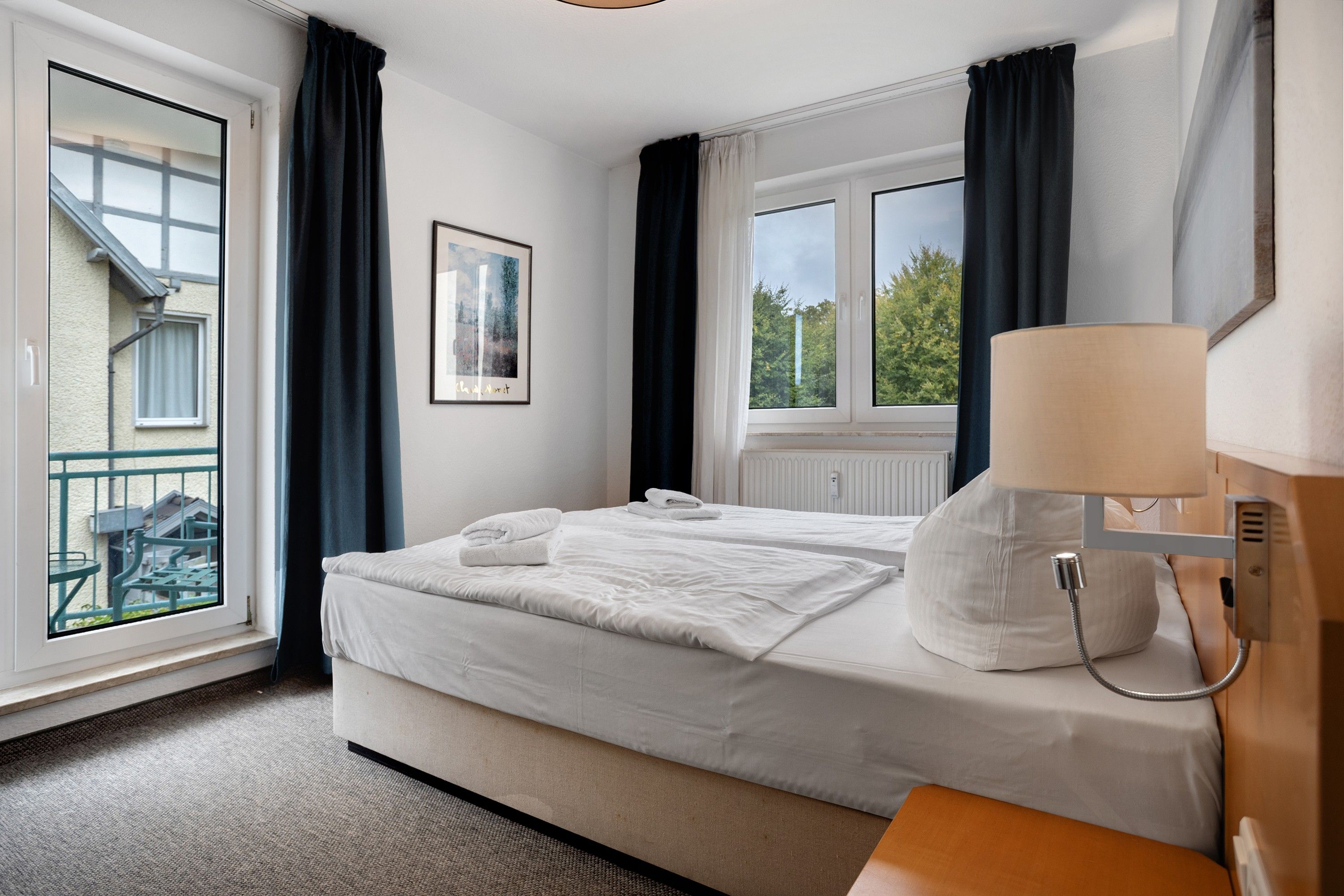 Une chambre d’hôtel avec un lit, une fenêtre, une vue sur l’extérieur et une lampe.