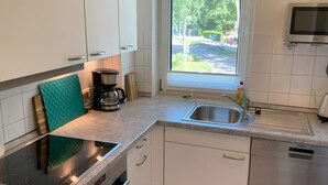 Una cucina moderna con piano cottura integrato, macchina da caffè, lavandino e finestra vista strada.