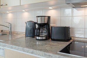Eine Küche mit Kaffeemaschine, Wasserkocher und Topf auf der Arbeitsfläche.