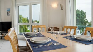 Comedor con una mesa lista para cuatro, incluyendo platos, cubiertos y vasos.