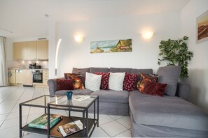 A modern living room with a grey sofa, a glass coffee table, and a painting on the wall. - Apartment 'Sonnenblick' with Balcony and Wi-Fi (Zempin)