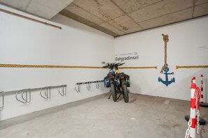 A motorcycle parked in a garage with a wall-mounted rack and a sign reading 'Fahrradinsel'. - Apartment 'Sonnenblick' with Balcony and Wi-Fi (Zempin)