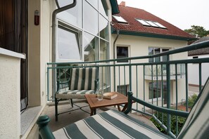 Ein Balkon mit einem Stuhl, einem kleinen Tisch und einem Glas Wasser.