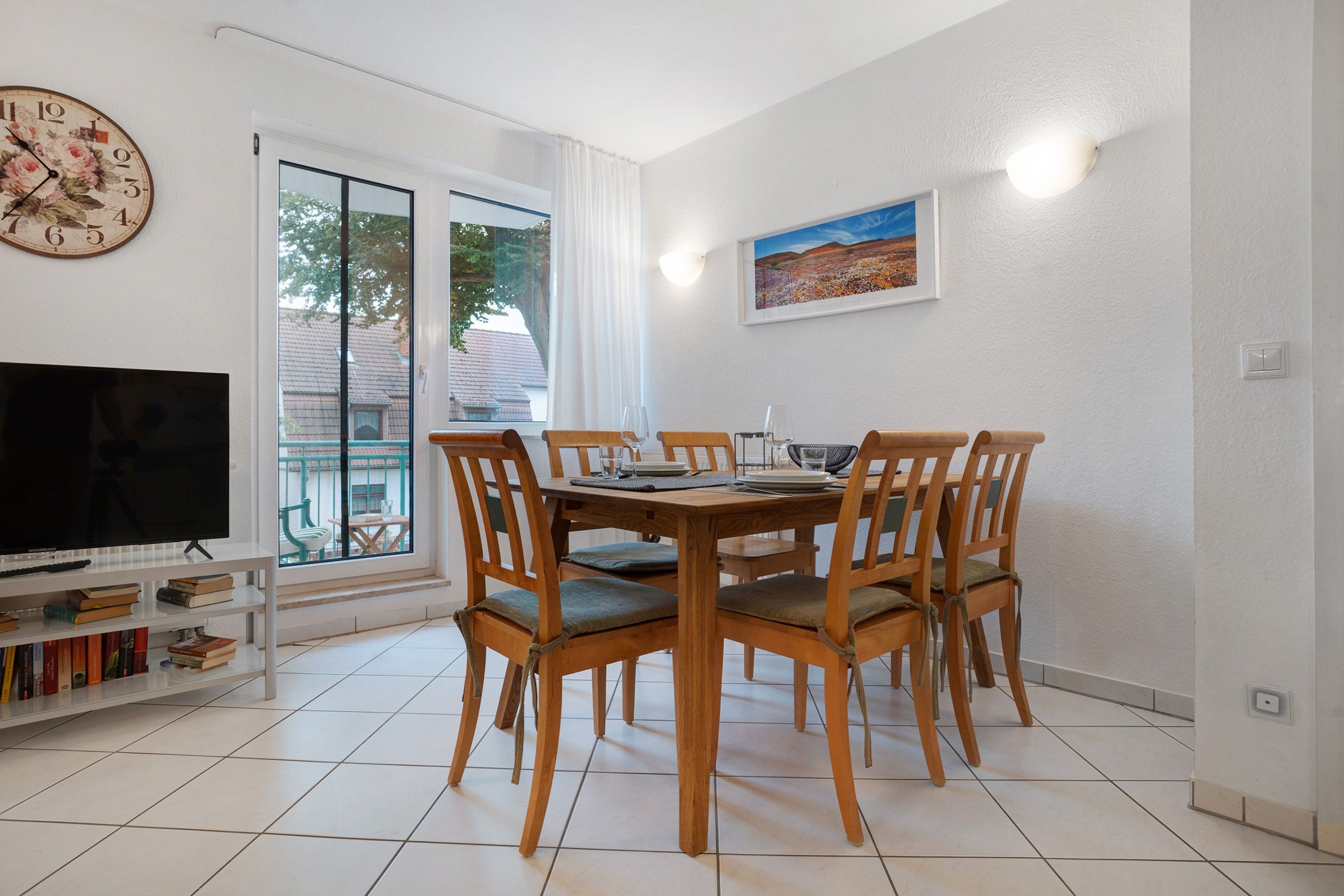 Un coin repas avec une table et des chaises en bois, un téléviseur et une bibliothèque.