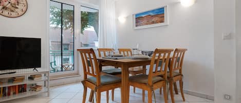 A dining area with a wooden table and chairs, a television, and a bookshelf.