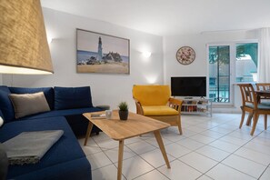 Ein Wohnzimmer mit einer Couch, einem Couchtisch, einem Fernseher und einem Essbereich mit Stühlen.
