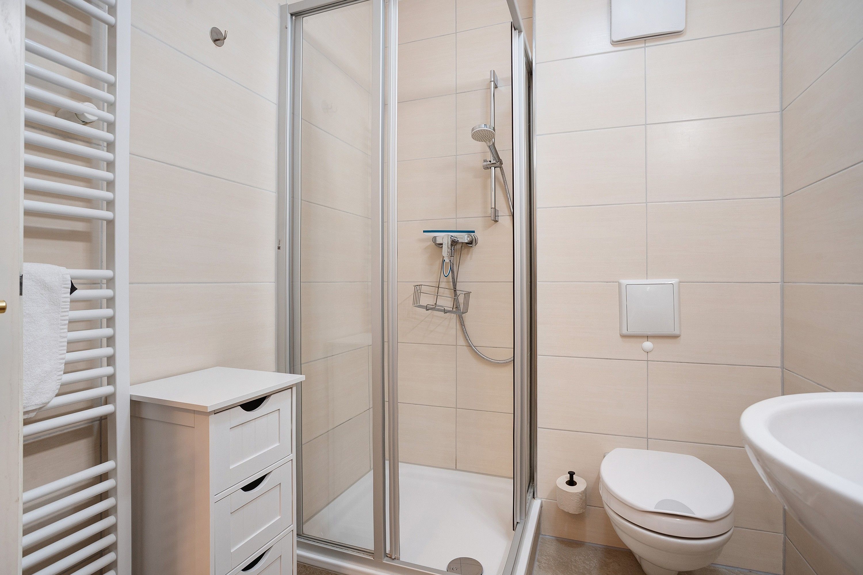 A bathroom with a glass-enclosed shower, a toilet, and a sink.