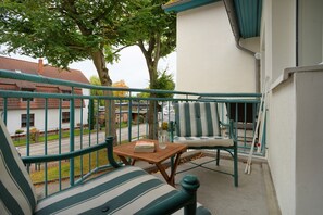 Ein Balkon mit einem Holztisch, einem gestreiften Kissen und einem Stuhl.