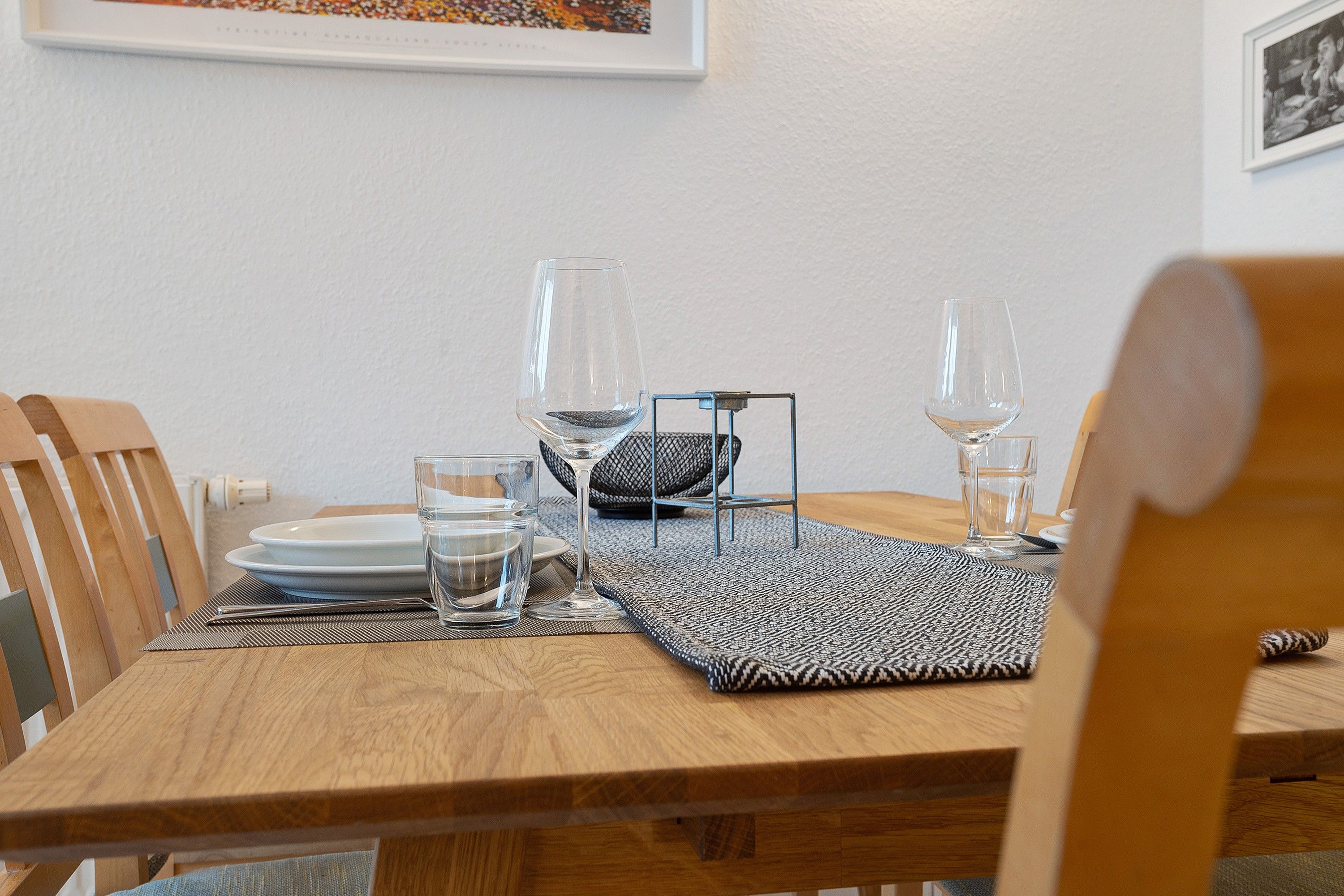 Een houten eettafel gedekt met borden, glazen en een waterfles.