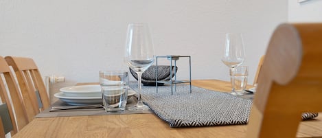 A wooden dining table set with plates, glasses, and a water bottle.