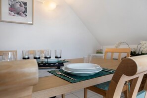 A dining table set with plates, glasses, and cutlery, with a framed picture on the wall. - Apartment 'Ostseezauber' 75 m², 3 Rooms, Balcony, up to 4 Guests (Zempin)