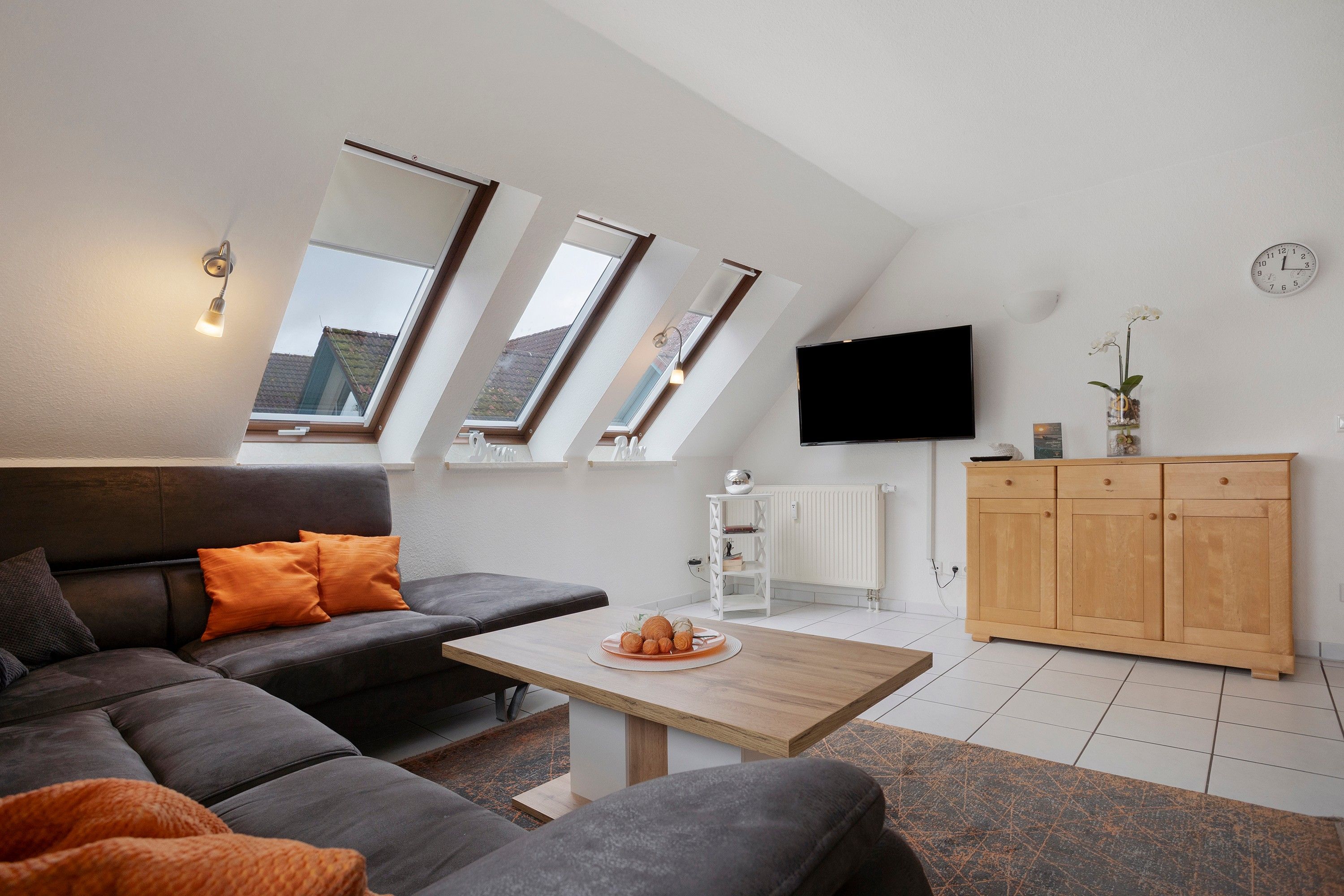 Un salon moderne avec un canapé, une table basse et un téléviseur fixé au mur.