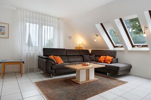 A modern living room with a sectional sofa, a coffee table, and a small side table. - Apartment 'Ostseezauber' 75 m², 3 Rooms, Balcony, up to 4 Guests (Zempin)