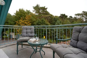 A balcony with two grey cushioned chairs, a small round table, and a glass of water. - Apartment 'Ostseezauber' 75 m², 3 Rooms, Balcony, up to 4 Guests (Zempin)