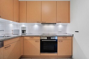 A modern kitchen with wooden cabinets, a built-in oven, and a coffee maker. - Apartment 'Jette' with Balcony and Wi-Fi (Zempin)