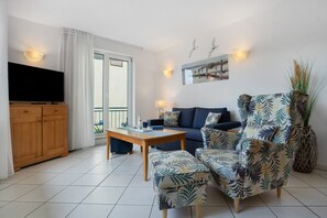 Een woonkamer met een bank, fauteuil, salontafel en een televisie.