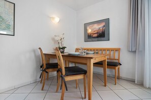 Un comedor con una mesa y sillas de madera, un jarrón con flores y un cuadro en la pared.