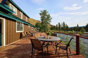 Eine Holzterrasse mit Sitzgelegenheiten und Blick auf einen Fluss.