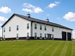 A large, single-story building with a flat roof, multiple windows, and a black garage door.