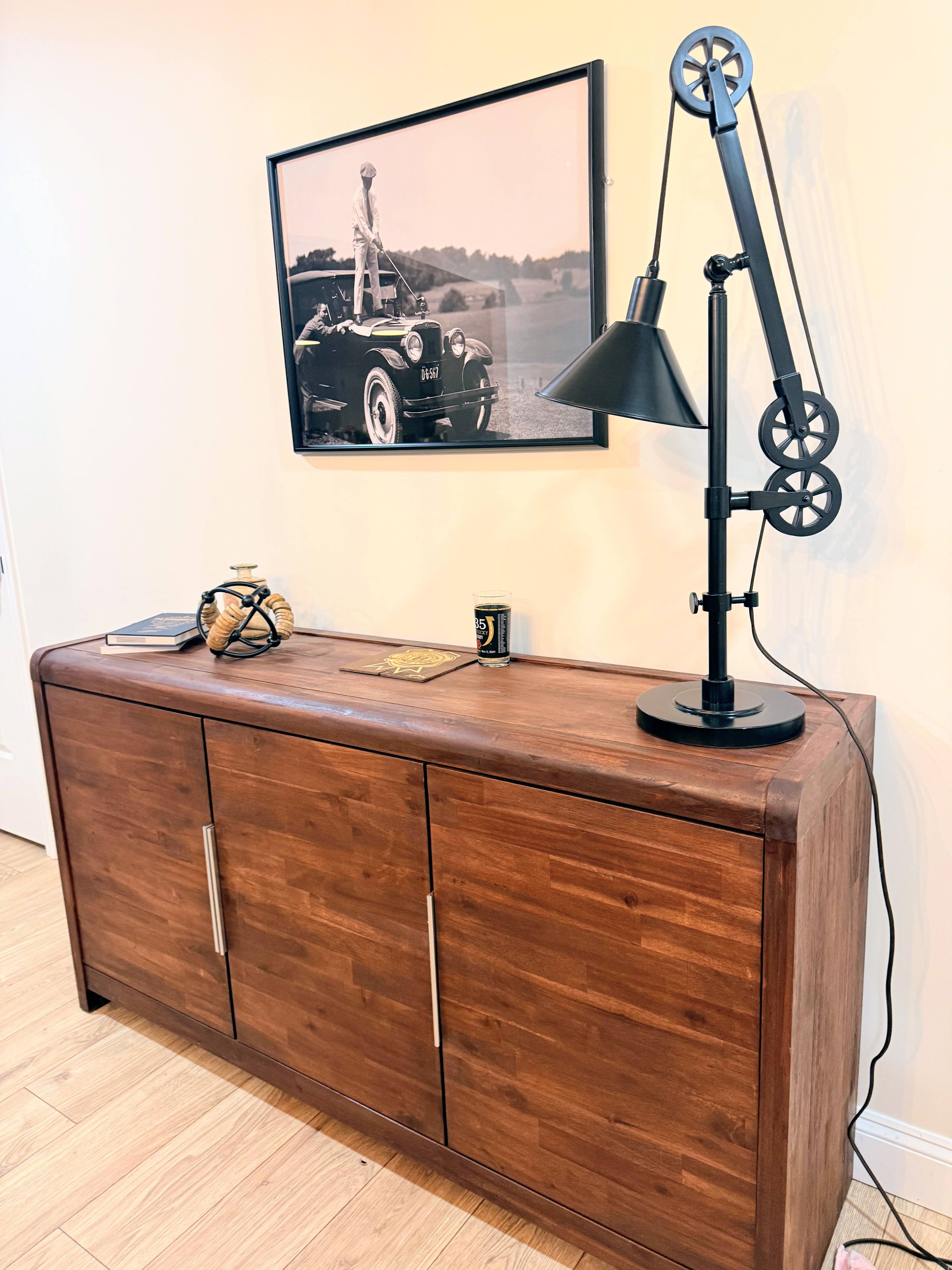 A wooden cabinet with a vintage car photograph above it.