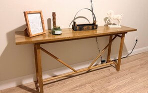 A wooden desk with a framed picture, a green bottle, a metal object, and a white statue.
