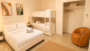 A bedroom with a bed, a bunk bed, a chair, a closet, and a rug.