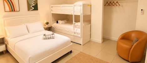 A bedroom with a bed, a bunk bed, a chair, a closet, and a rug.