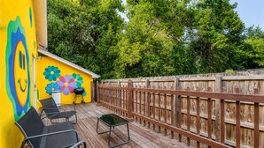 A wooden deck with outdoor furniture and a colorful mural on the wall.