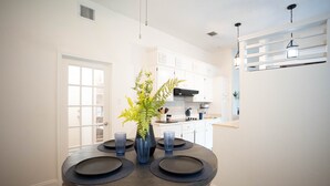 A dining area with a round table, blue glassware, and a potted plant.
