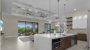Una cocina moderna con una isla central, electrodomésticos integrados y un comedor con vistas.