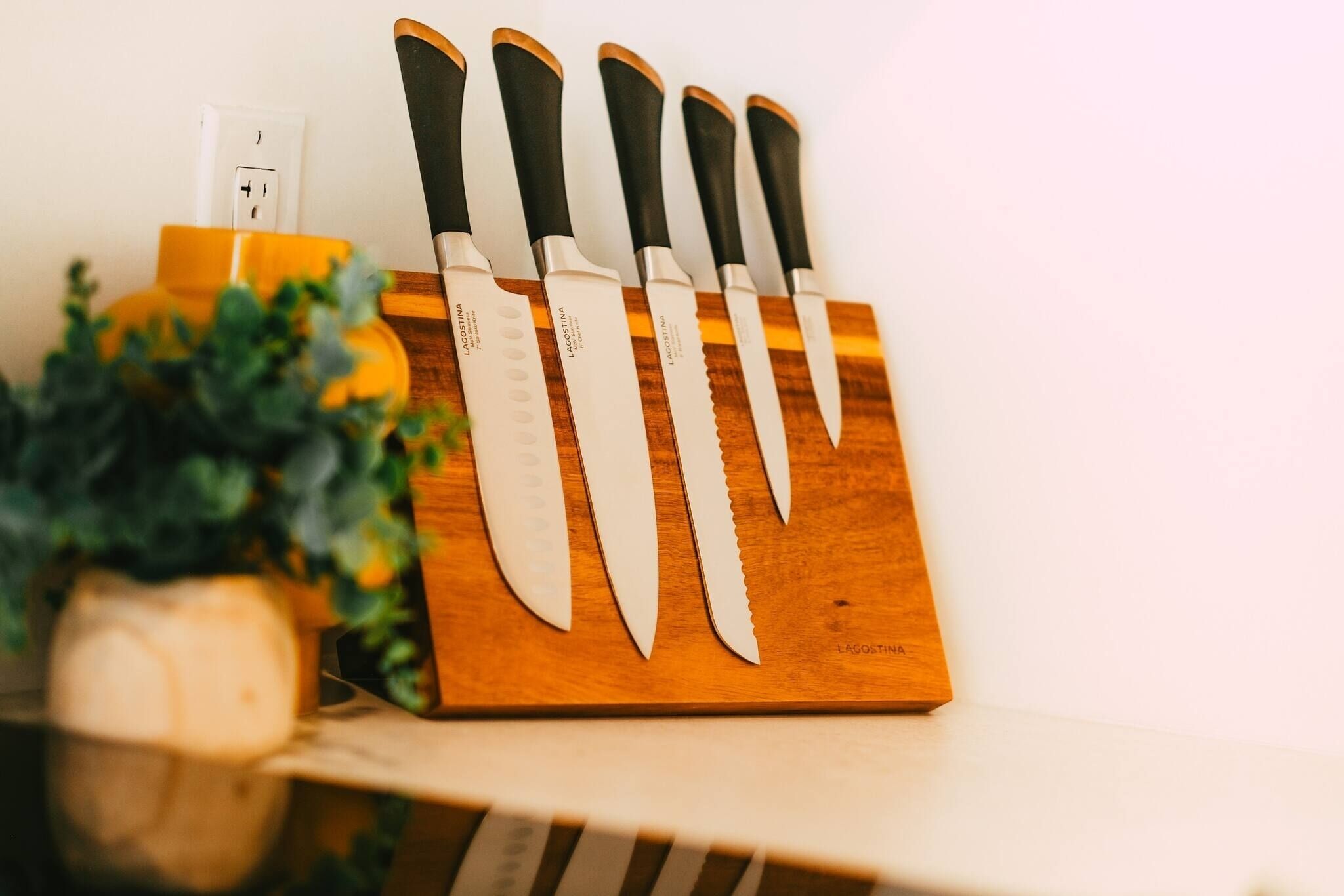 A knife block with six knives on a wooden surface.