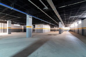 An indoor parking garage with concrete pillars, blue and white lighting, and a 'BLOCH' sign. - DAR DYAFA VIP (Agadir)