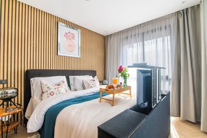 A hotel room with a bed, a bedside table, a TV, and a window with curtains. - DAR DYAFA VIP (Agadir)