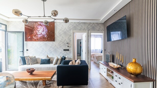 Una sala de estar moderna con un sofá, una mesa de centro y un televisor montado en la pared.