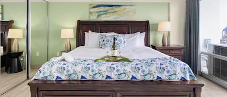 A hotel room with a large bed, a bedside table with a lamp, a mirror, and a window with curtains.