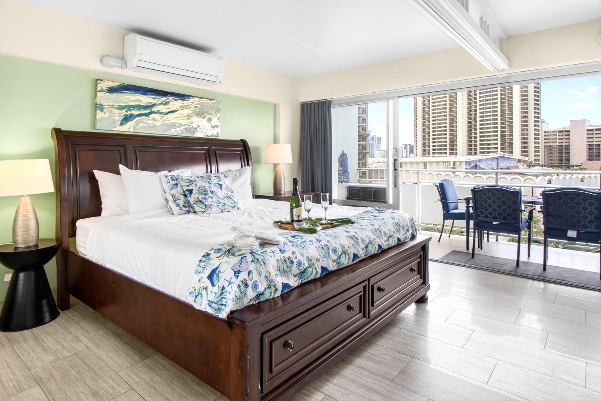 A hotel room with a large bed, a balcony with a view of the city, and a window with curtains.