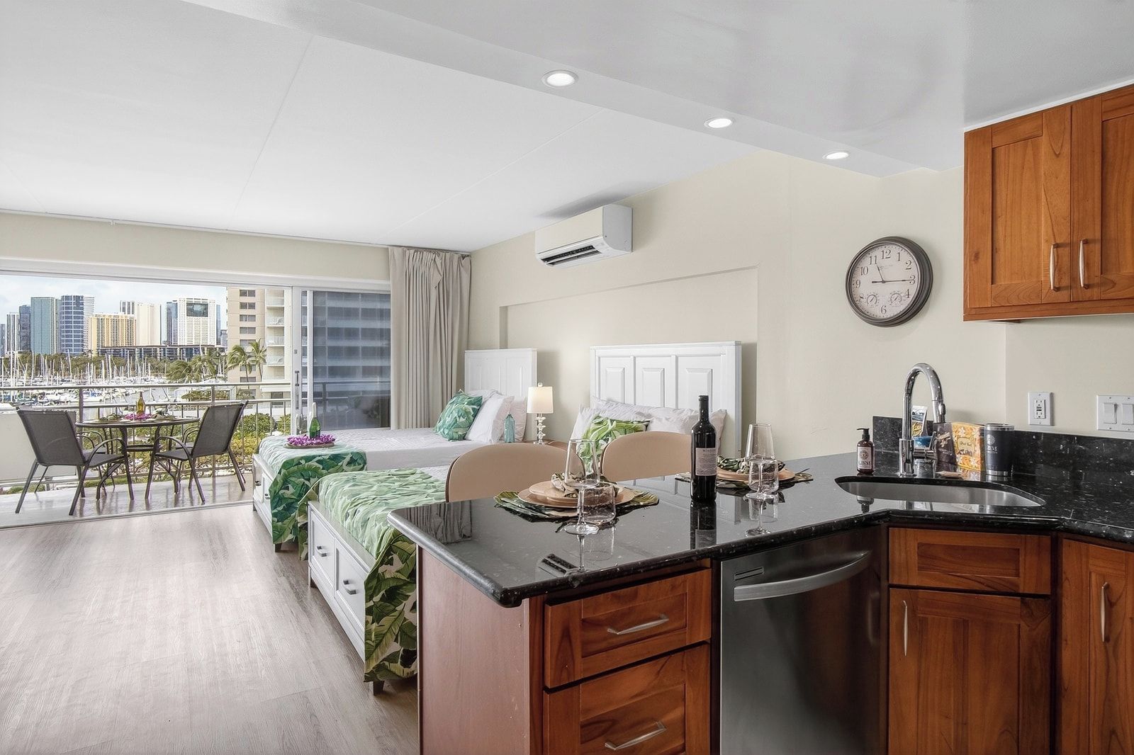 Une chambre d’hôtel moderne avec balcon, un coin cuisine et vue sur le paysage urbain.