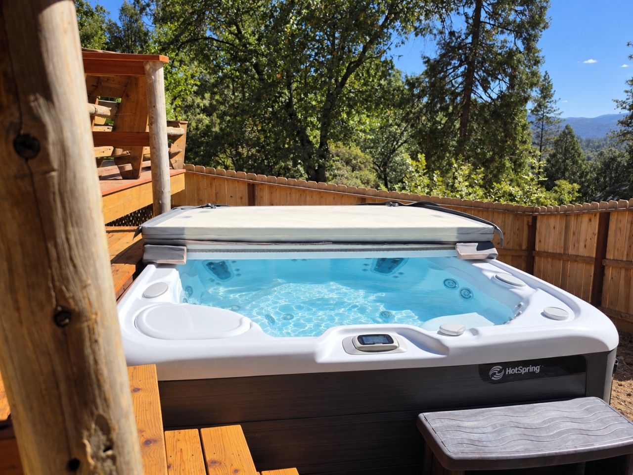 Un bain à remous avec une terrasse en bois et une vue sur les arbres et les montagnes.