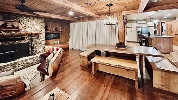 A rustic interior with a stone fireplace, wooden furniture, and a kitchen area.